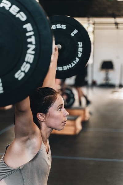 Topless, wearing black shorts, holding a black barbells
